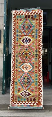 Lot 946 - A 20th century Chobi Kilim runner, worked in...