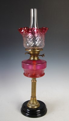 Lot 284 - A brass and ruby glass paraffin burning oil...