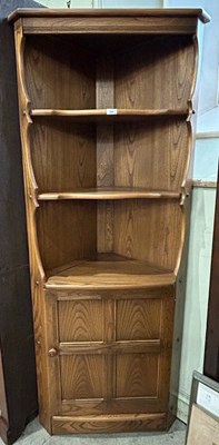 Lot 565 - An Ercol corner cabinet with three open...