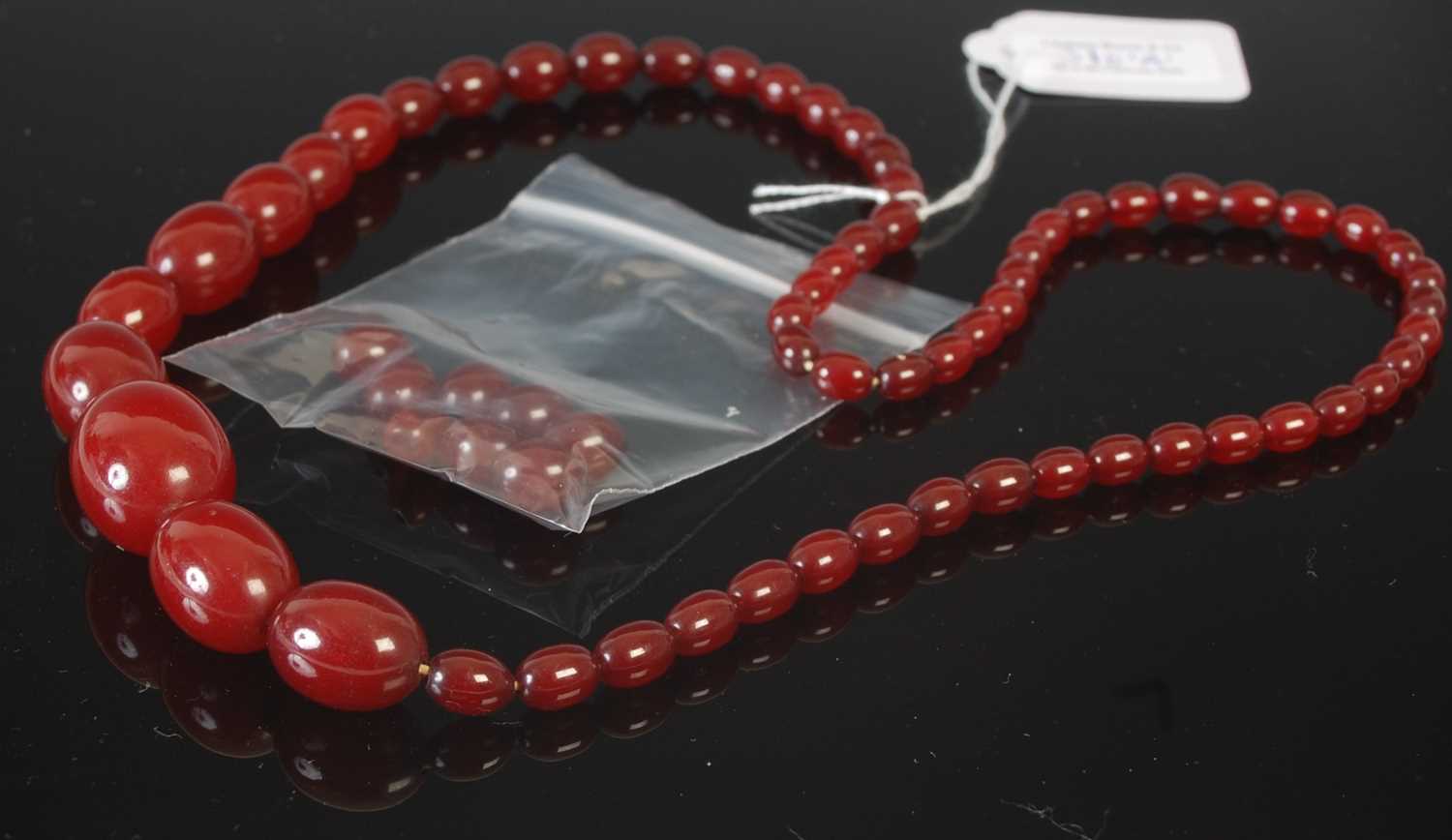 Lot 310 - A red amber type graduated bead necklace;...