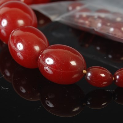 Lot 310 - A red amber type graduated bead necklace;...