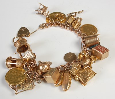 Lot 635 - A 9ct gold charm bracelet suspending twenty...