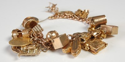 Lot 635 - A 9ct gold charm bracelet suspending twenty...