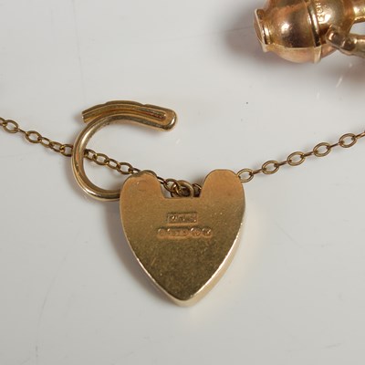 Lot 635 - A 9ct gold charm bracelet suspending twenty...