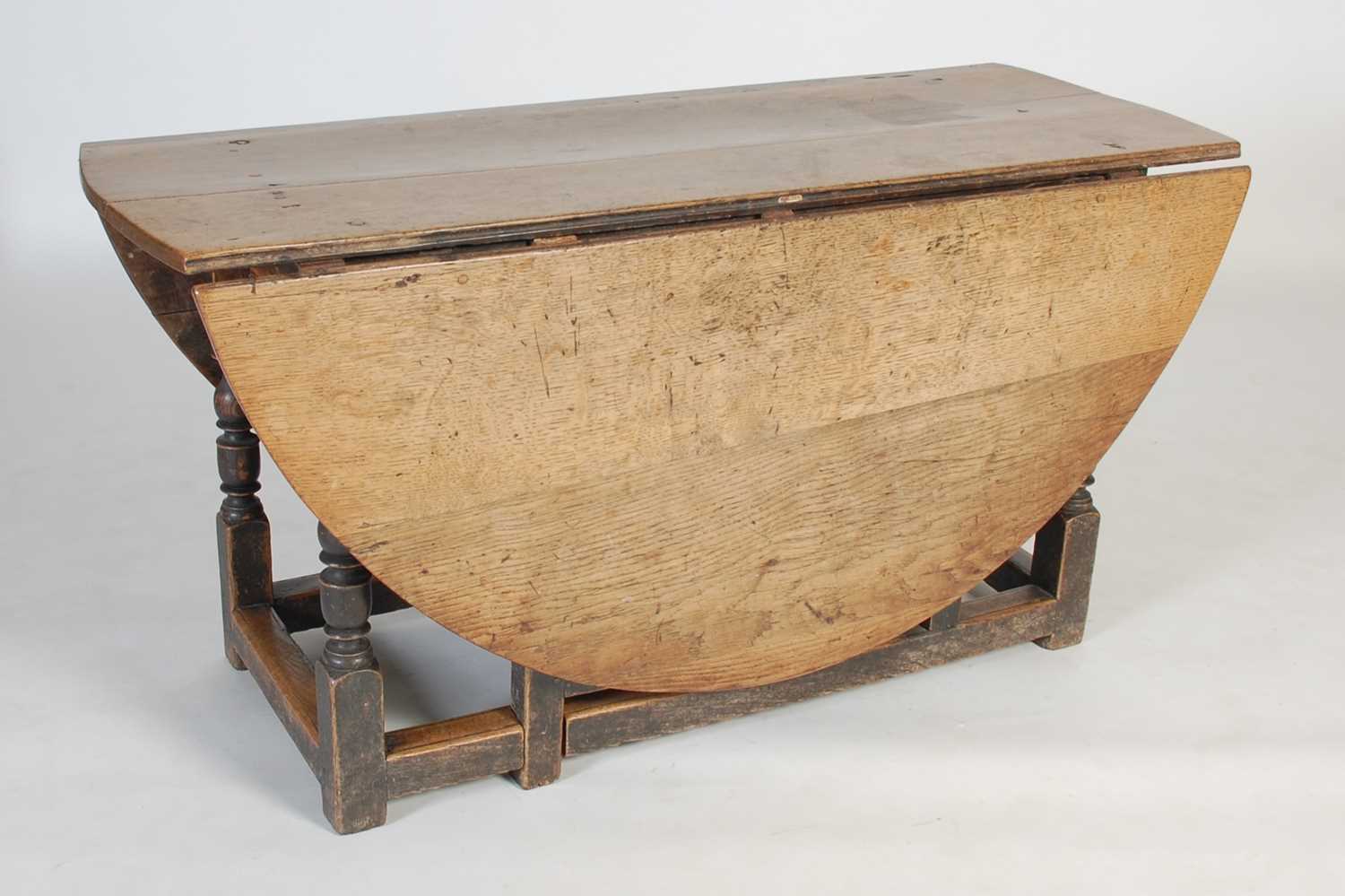 Lot 13 - An antique oak gate-leg dining table, the oval...
