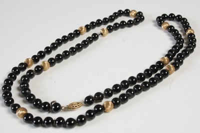 Lot 575 - A black onyx and yellow metal bead necklace,...
