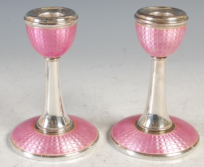 Lot 228 - A pair of silver and pink enamel candlesticks,...