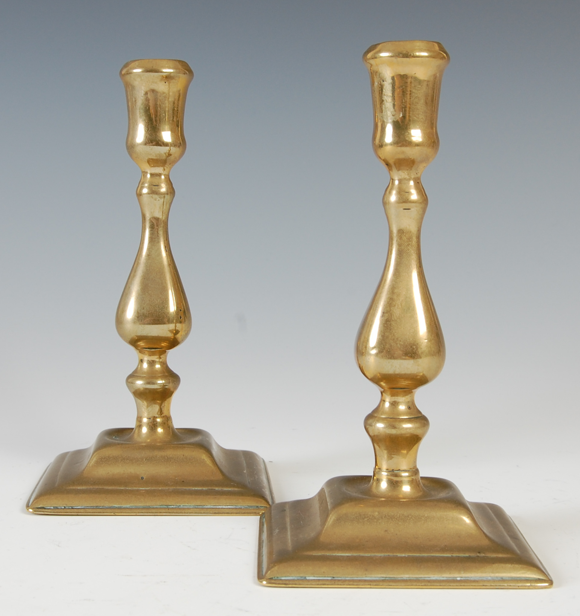 Lot 148 A pair of antique brass candlesticks, the