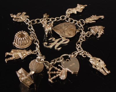 Lot 46 - A white metal charm bracelet, suspending nine...