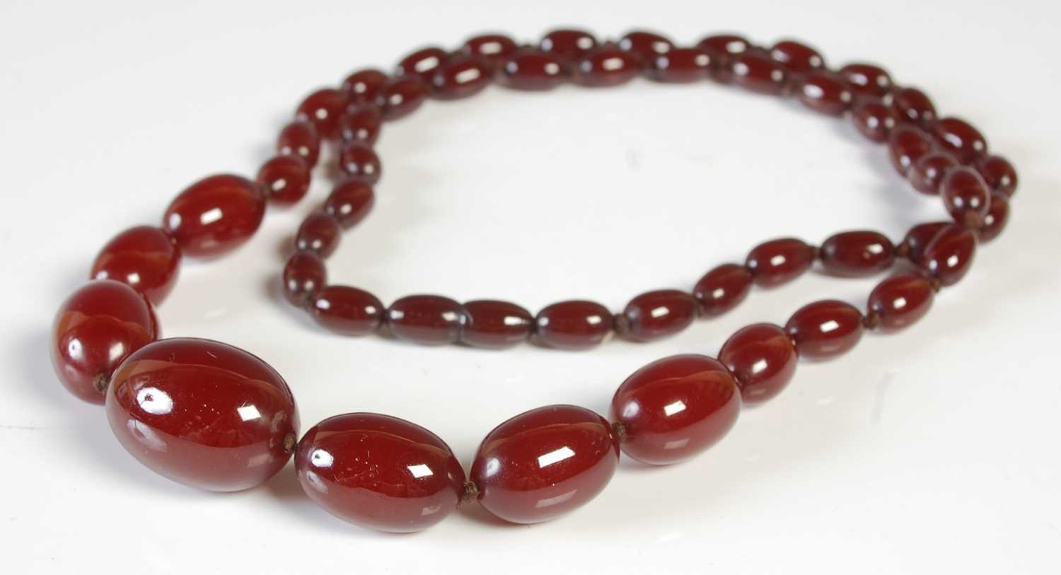 Lot 95 - A red amber type graduated bead necklace,...