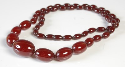 Lot 95 - A red amber type graduated bead necklace,...