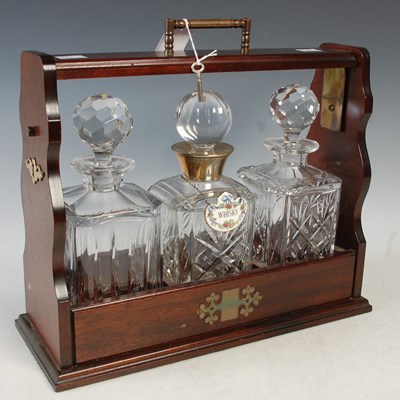 Lot 363 - A mahogany three bottle tantalus, the centre...