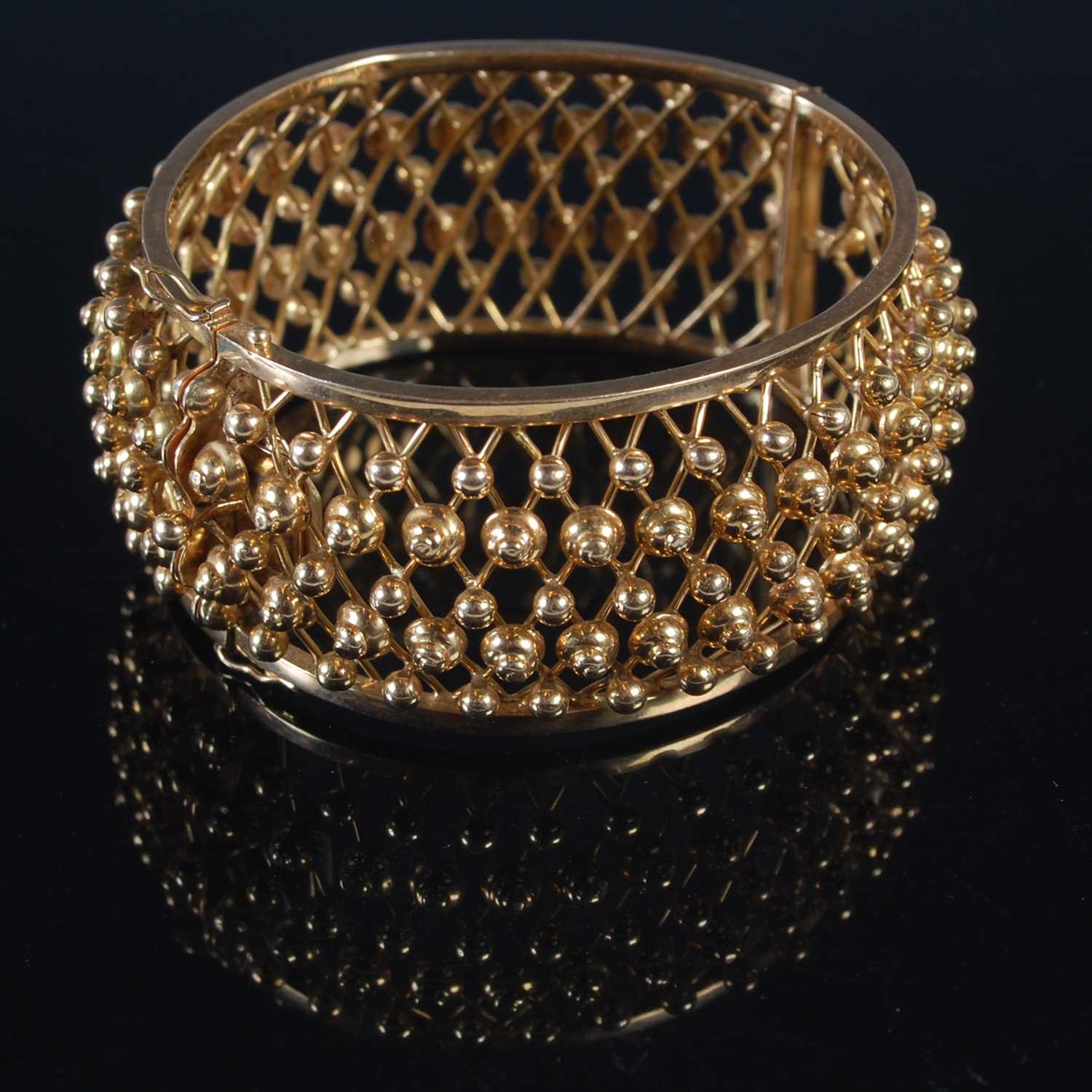 Lot 255 - A yellow metal hinged bracelet of convex form,...