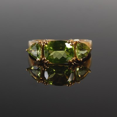 Lot 312 - A 9ct gold and peridot three stone dress ring,...
