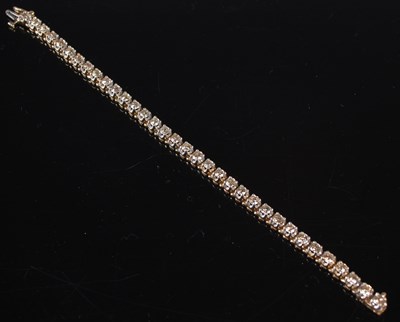 Lot 438 - A yellow metal diamond set tennis bracelet,...
