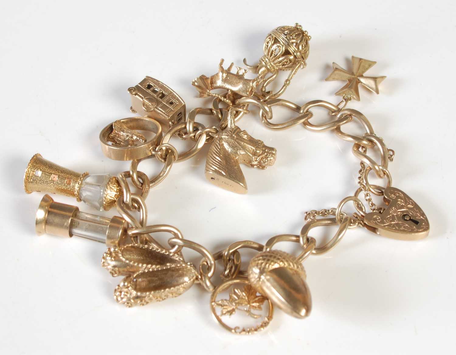 Lot 174 - A 9ct gold charm bracelet suspending 11...