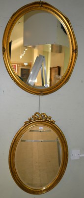 Lot 1034 - A reproduction oval gilt wall mirror, the top...