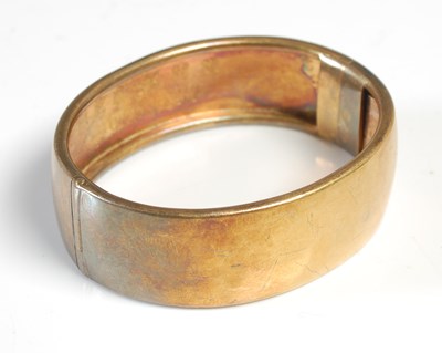 Lot 400 - A late 19th century yellow metal hinged bangle,...