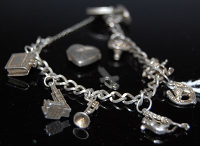 Lot 74 - A white metal charm bracelet suspending...