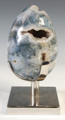 Lot 390 - A carved moss agate crystal geode egg, raised...