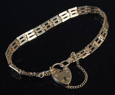 Lot 32 - A 9ct gold gatelink bracelet, with heart...