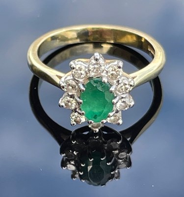 Lot 94 - An 18ct gold, emerald and diamond cluster ring,...