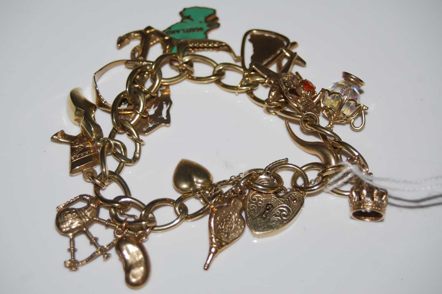 Lot 60 - A 9ct gold charm bracelet suspending eighteen...