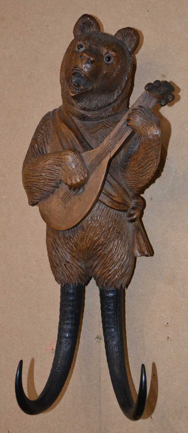 Lot 104 - A Black Forest carved wood musical wall hook...