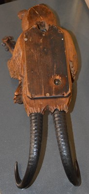 Lot 104 - A Black Forest carved wood musical wall hook...