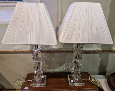 Lot 564 - A pair of clear faceted tables lamps and shades.