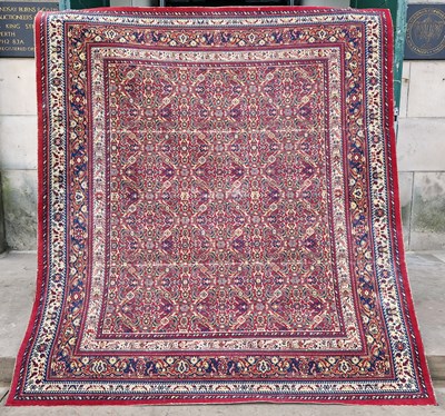 Lot 761 - A machine made Persian style madder ground rug,...