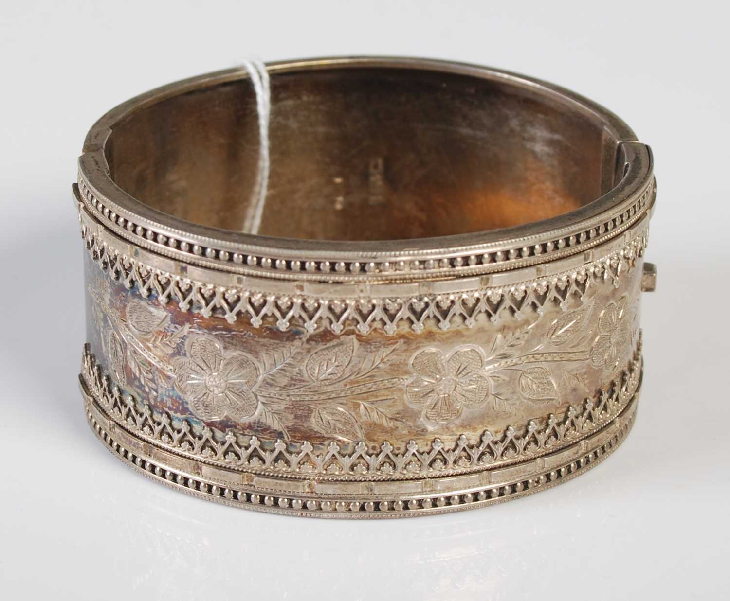 Lot 169 - A hinged white metal bangle with engraved...